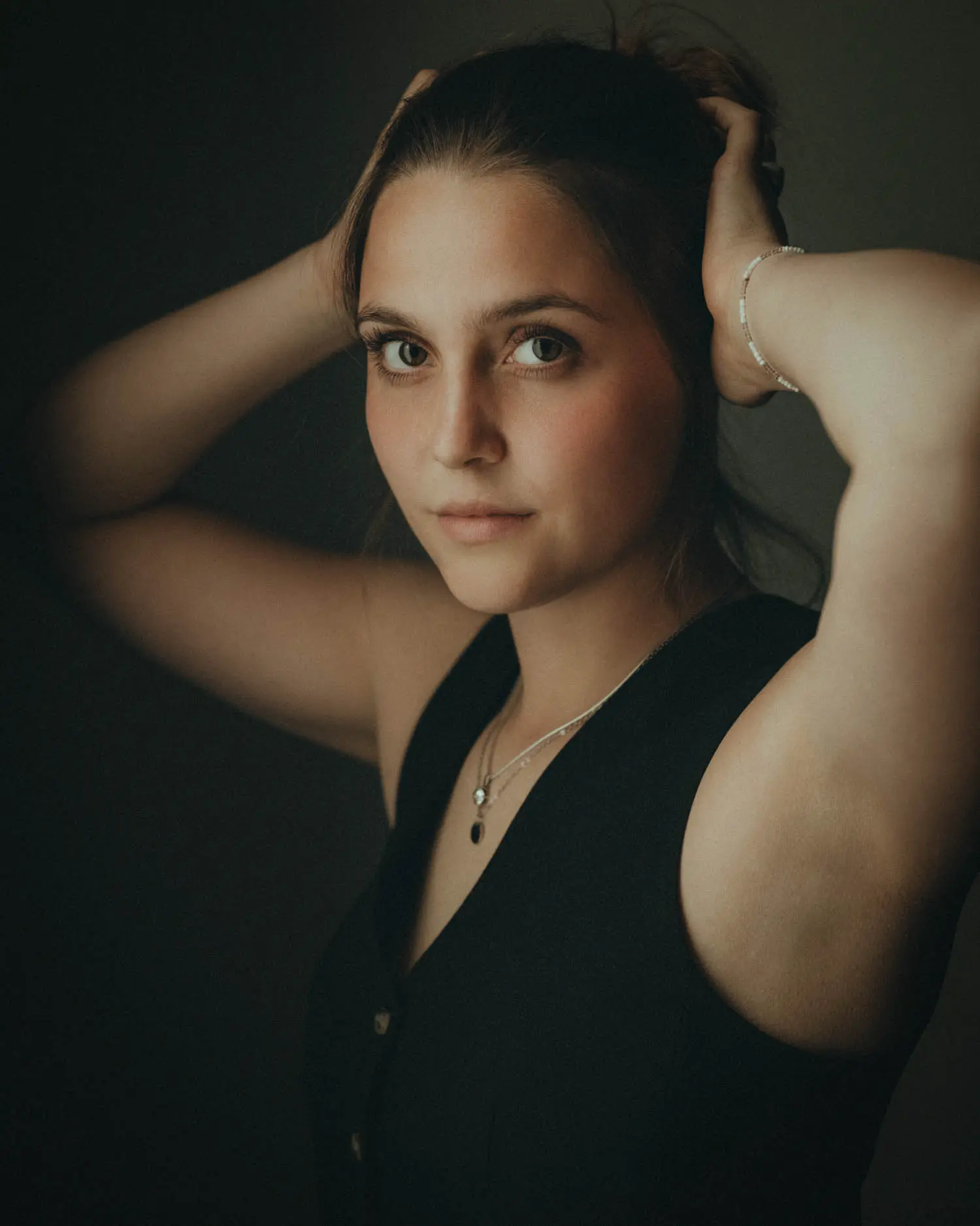 Dunkles Close-up mit Händen im Haar und intensivem Blick ins Licht