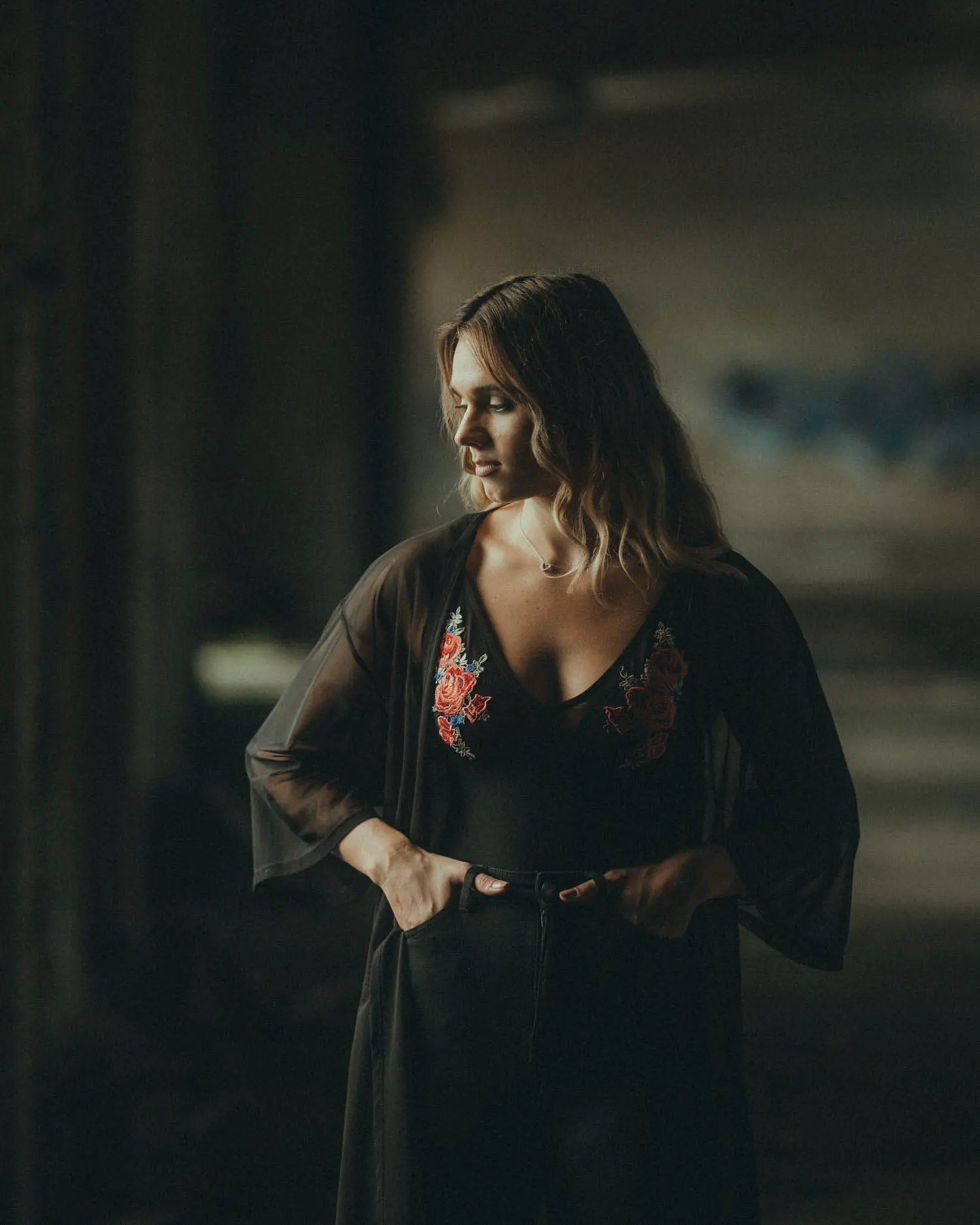 Frau in dunklem Outfit vor tiefem Hintergrund, das Licht zeichnet klar das Gesicht