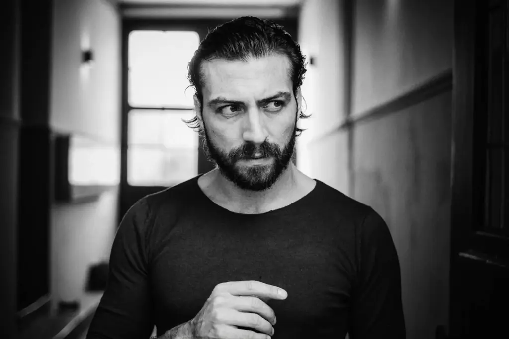 Schwarzweißporträt eines Mannes in einem langen Flur mit starker Perspektive