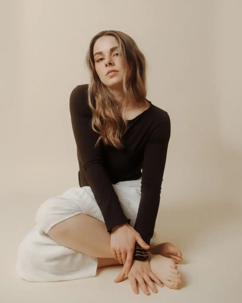 Sitzendes Studio-Portrait vor hellem Hintergrund, ruhiger Blick und klare Haltung