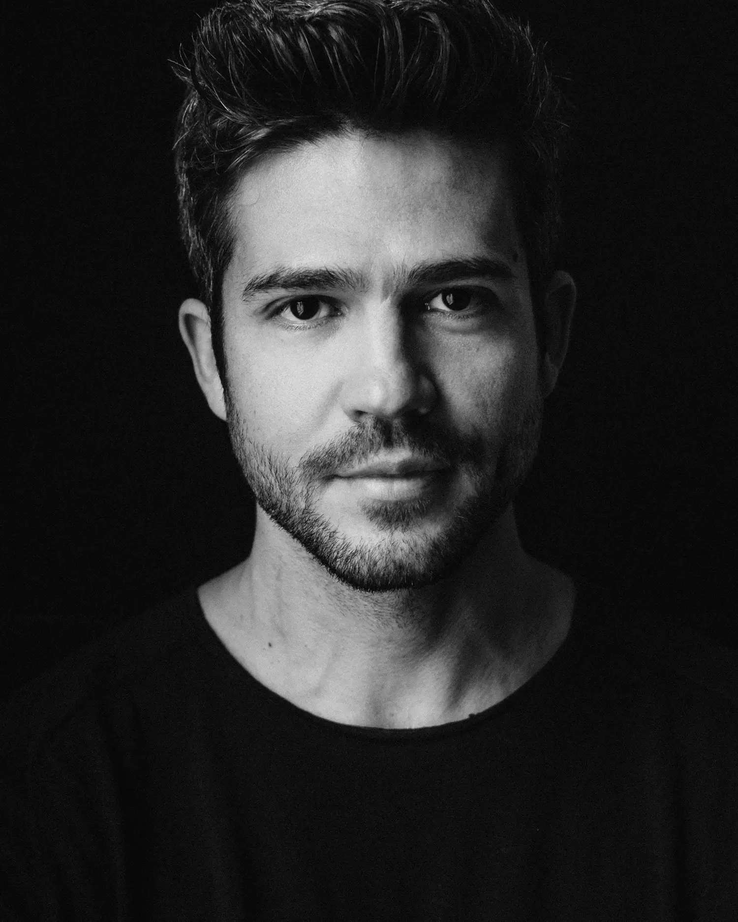 Kontrastreiches Schwarzweißporträt eines Mannes mit ruhigem, direktem Ausdruck