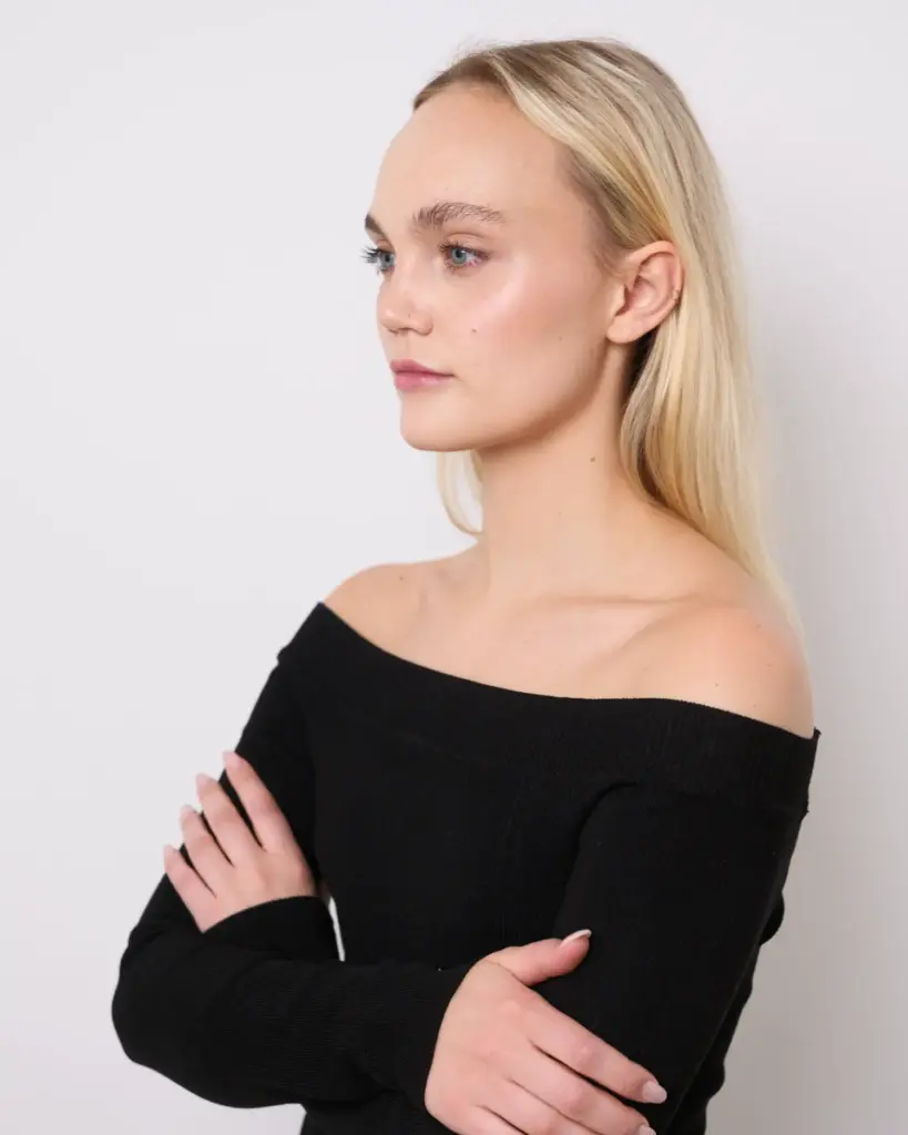 Model in schlichter Kleidung vor neutralem Hintergrund