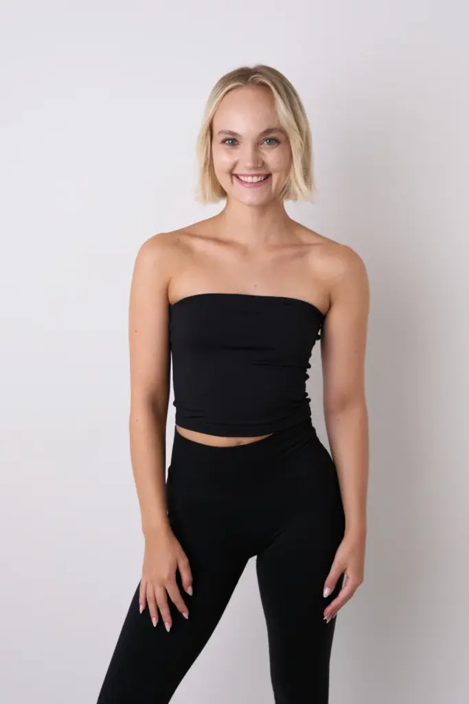 Lächelndes Model im schwarzen Outfit frontal vor hellem Hintergrund