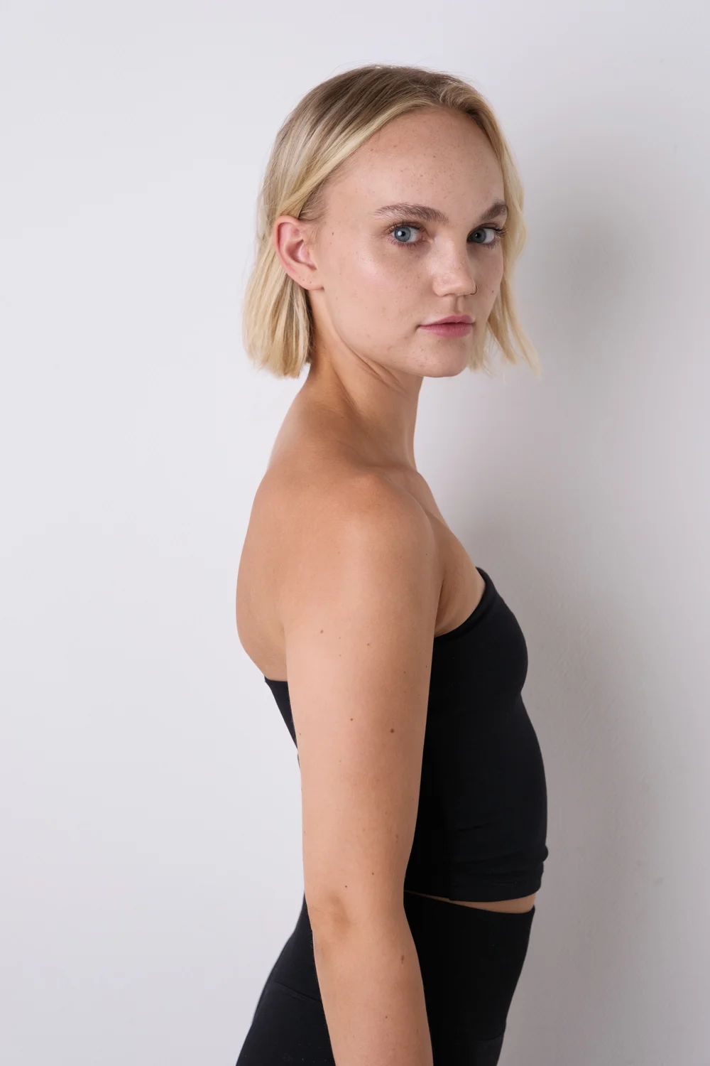 Model im schwarzen Top seitlich gedreht, mit Blick zur Kamera