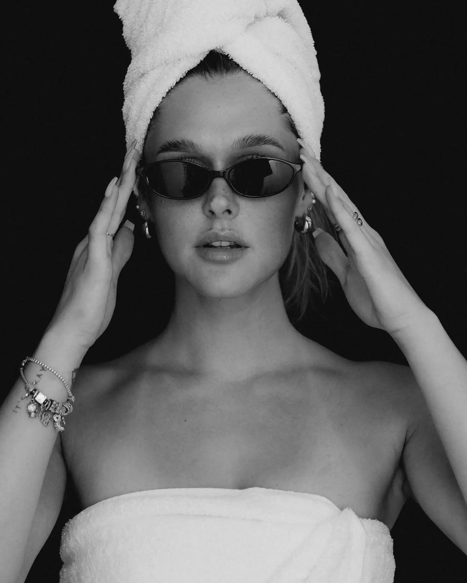 Schwarzweißportrait eines Models mit Sonnenbrille und Handtuch um Kopf und Oberkörper